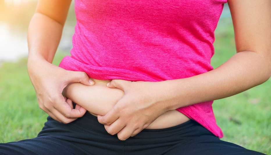 Mujer agarrando sus rollitos del abdomen