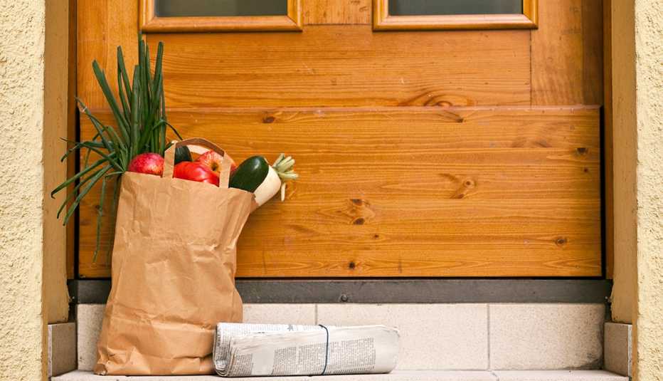 Bolso de víveres y un periódico frente a la puerta de una residencia