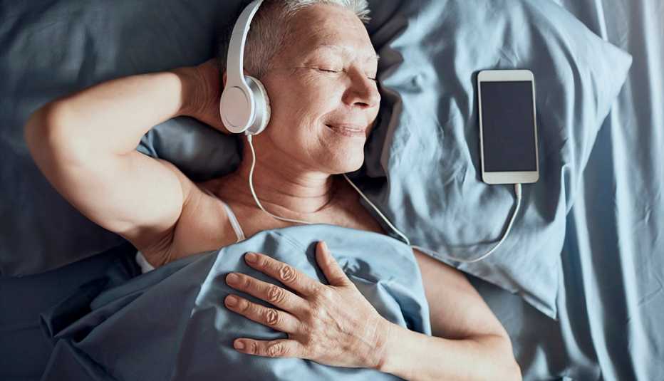 Una señora mayor escuchando música mientras está acostado en la cama