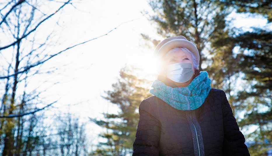 Una mujer, usando una mascarilla, camina al aire libre Una mujer, usando una mascarilla, camina al aire libre