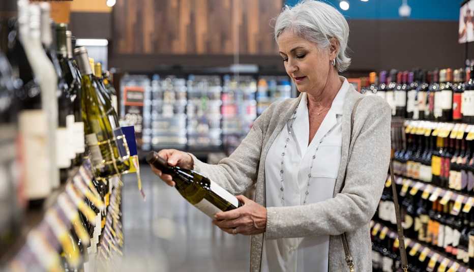 Una mujer lee la etiqueta de una botella de vino Una mujer lee la etiqueta de una botella de vino