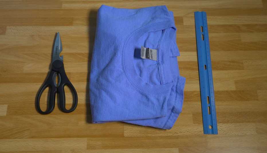 Tijeras, una camisa de algodón doblada y una regla sobre una mesa