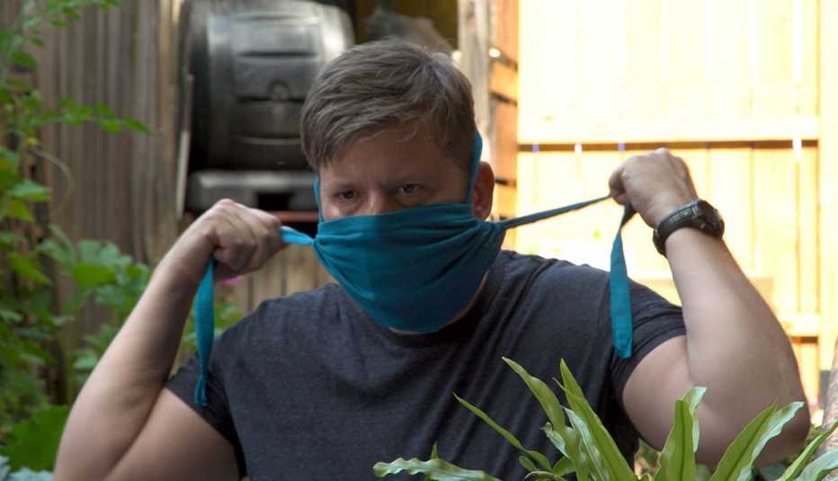 Un hombre se pone una mascarilla casera