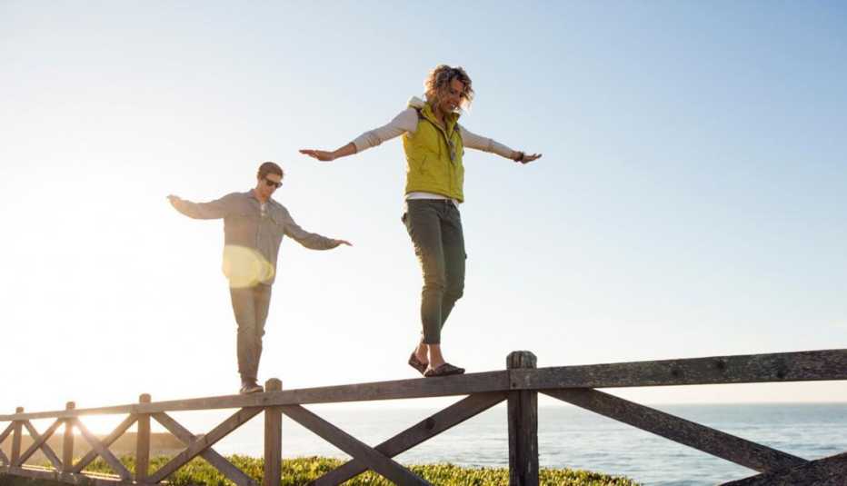 Pareja camina balanceándose sobre una valla