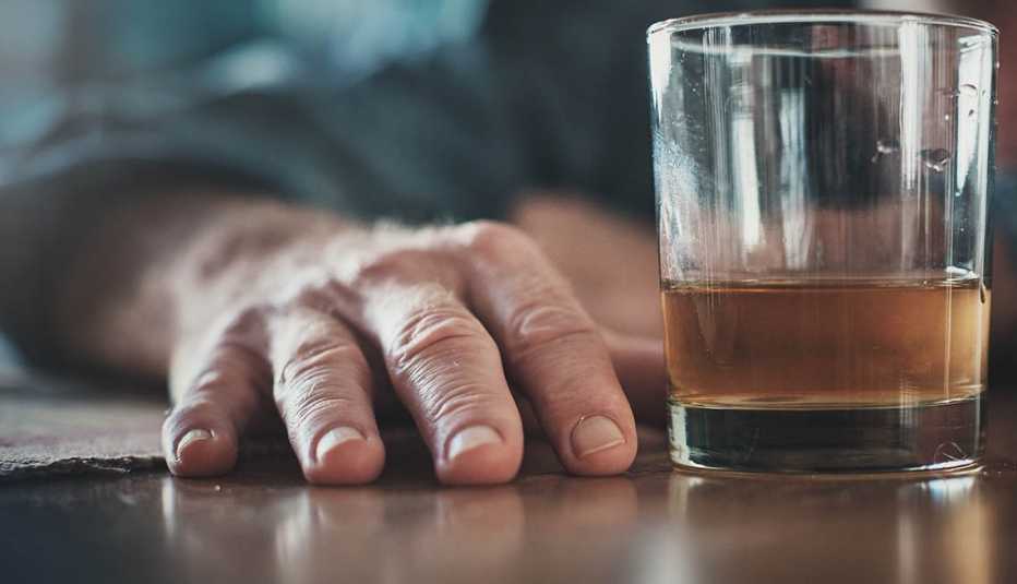 Mano de un hombre y un vaso con licor