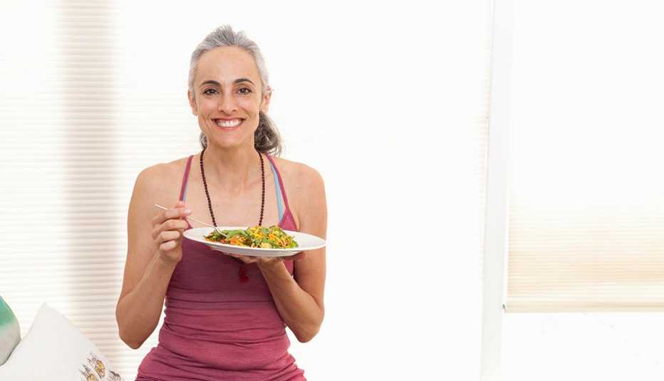 Una mujer sostiene un plato de comida Una mujer sostiene un plato de comida