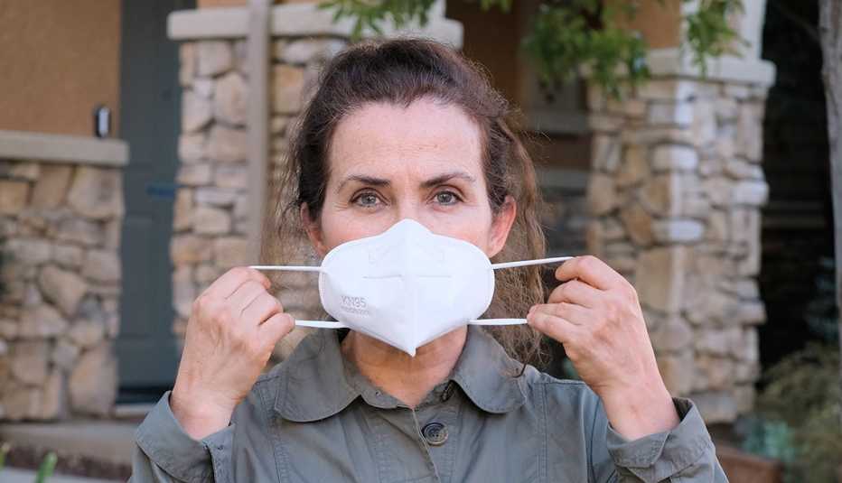 Una mujer se coloca una mascarilla