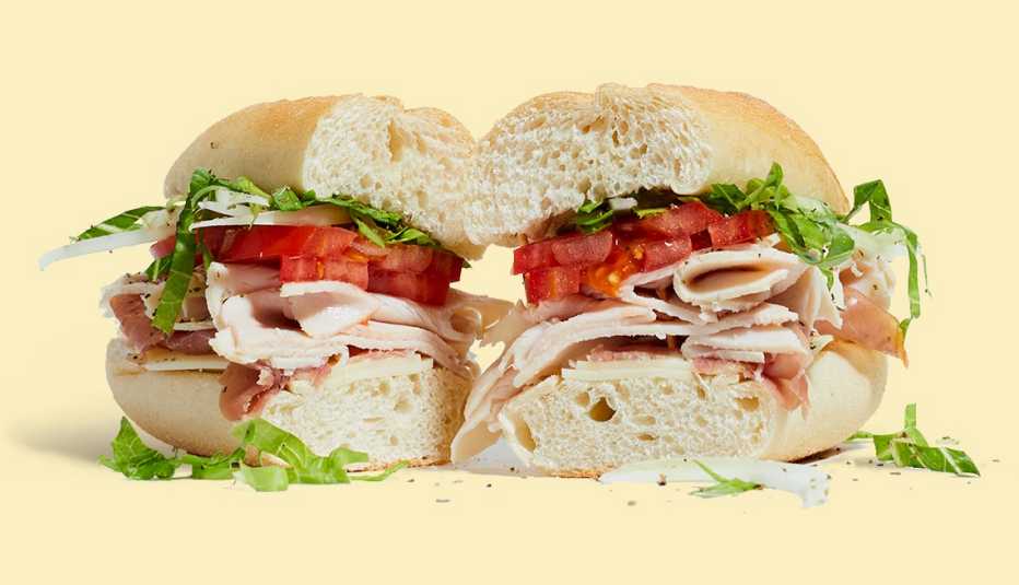 Sándwich con jamón de pavo, queso suizo, tomate y lechuga cortado a la mitad Sándwich con jamón de pavo, queso suizo, tomate y lechuga cortado a la mitad