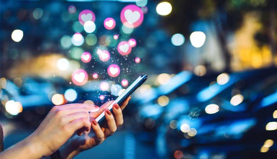 Corazones salen flotando de un teléfono mientras una mujer usa una aplicación de citas