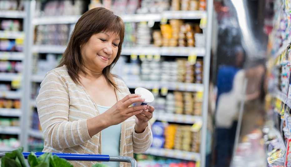Una mujer examina los nutrientes de un yogur en un supermercado Una mujer examina los nutrientes de un yogur en un supermercado
