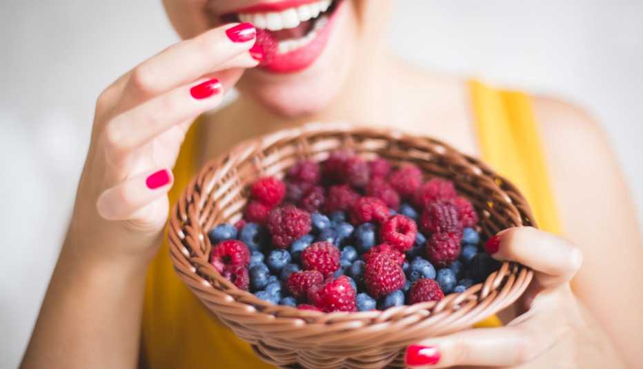 Una mujer comiendo moras de una canasta