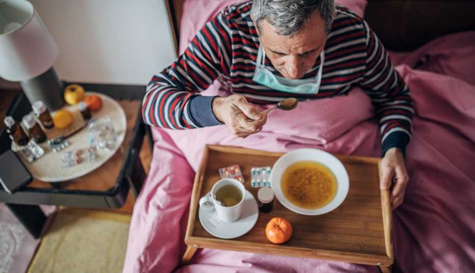 Un hombre come sopa de pollo en su cama