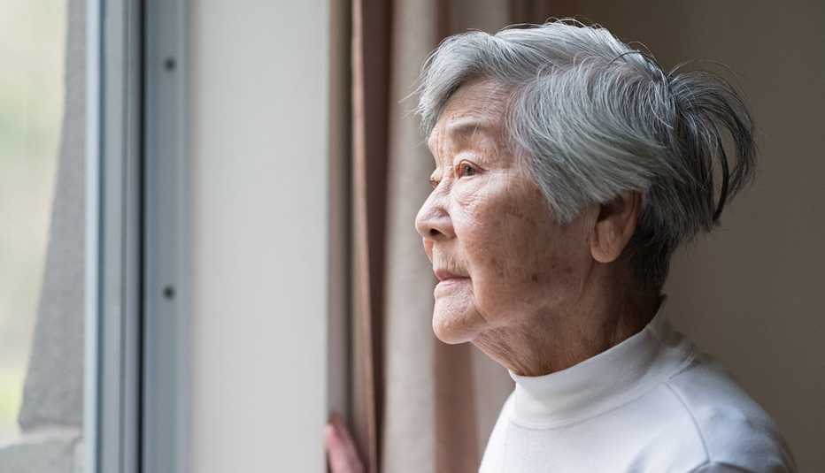 Una mujer asiática mira por una ventana Una mujer asiática mira por una ventana