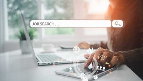 Mujer pone una mano sobre su tableta y la otra cerca a su computadora personal. Encima un letrero en inglés que dice búsqueda de trabajo. Mujer pone una mano sobre su tableta y la otra cerca a su computadora personal. Encima un letrero en inglés que dice búsqueda de trabajo.