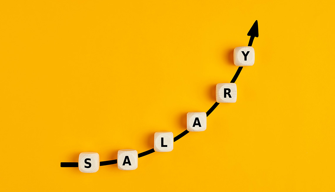 La palabra salary escrita en bloques de madera con un gráfico de flecha ascendente