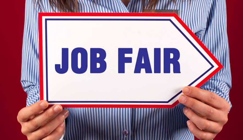 Persona con cartel en mano que dice feria de trabajo en inglés