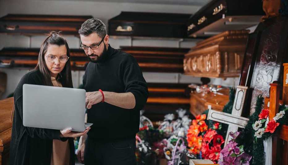 Coordinadores de duelo  en un salón de ataúdes revisan un computador.