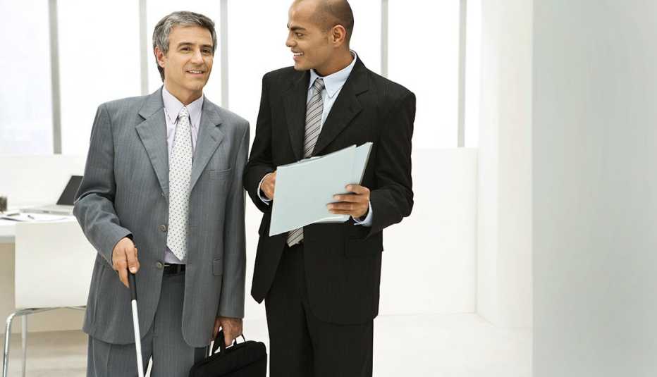 Hombre con discapacidad visual en traje de corbarta con un hombre al lado - Consejos para la búsqueda de trabajo con discapacidades visuales