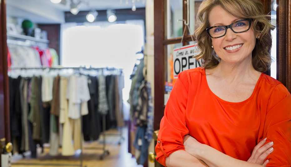 Mujer sonriente a la entrada de un almacén de ropa