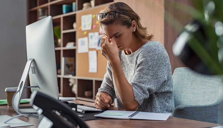 Mujer sentada frente a su computadora se toca el tabique con una mano en señal de preocupación