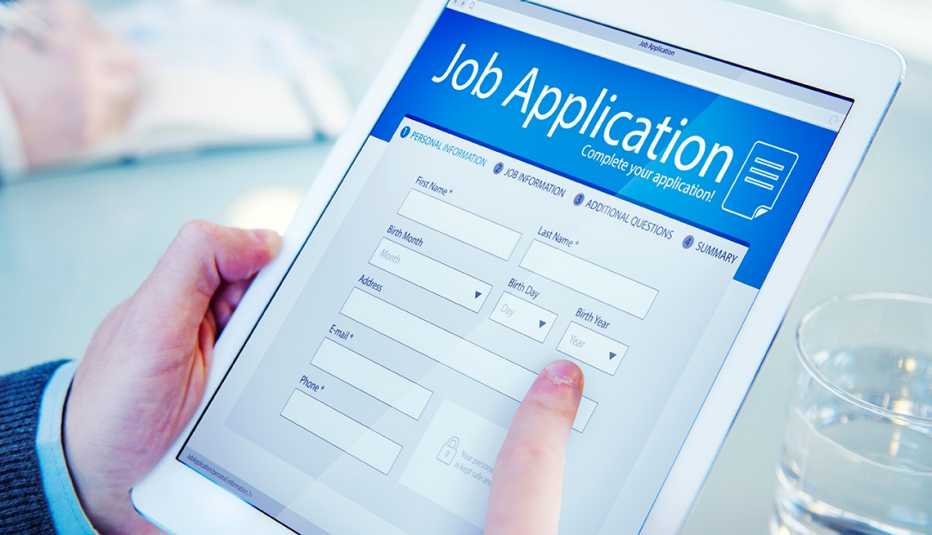 Manos de una persona sobre una tableta que muestra un formulario para una solicitud de trabajo.