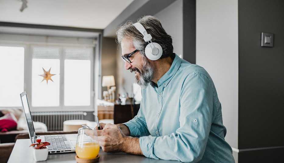 Hombre trabajando en una computadora desde la sala comedor de su casa