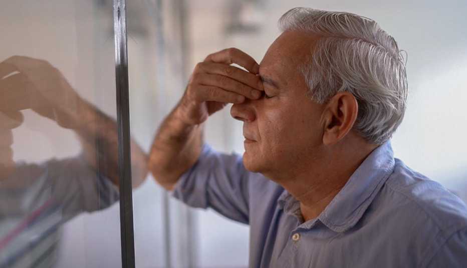 a man leaning on a wall with his head in his hand