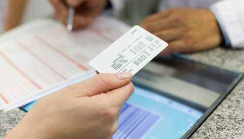 Persona sosteniendo una tarjeta de seguro médico.