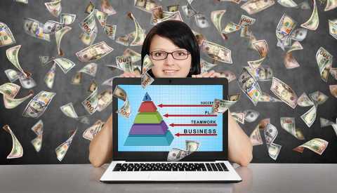 Mujer con una computadora y billetes de 100 dólares volando detrás de ella.