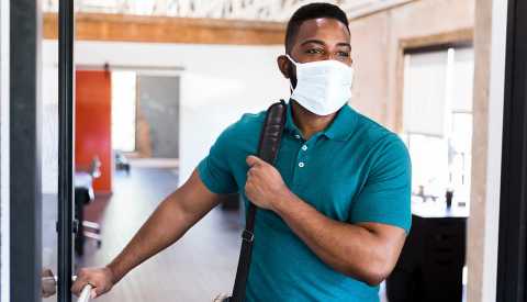Hombre con una mascarilla entrando a una oficina.