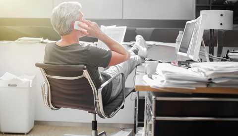 Hombre con ropa informal y poniendo los piés en un escritorio
