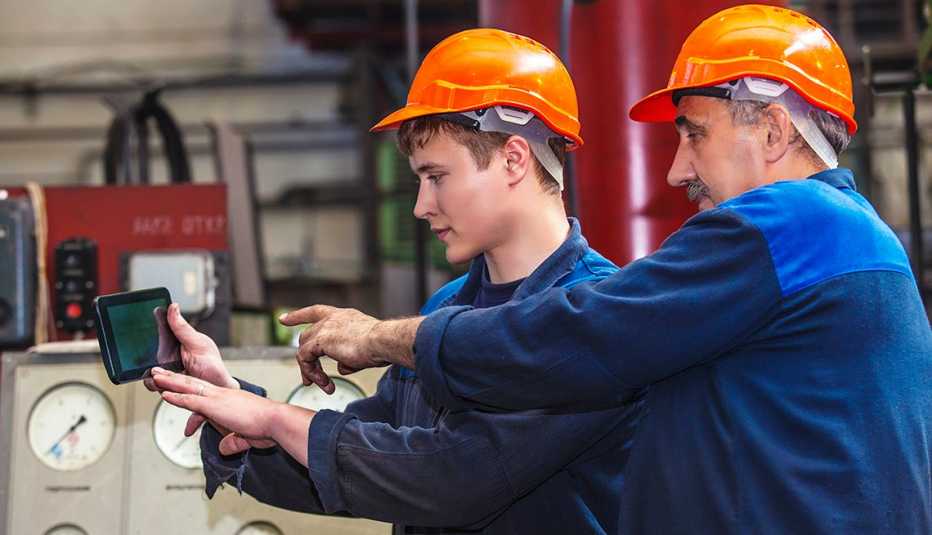 Hombre mayor monitorea el trabajo de uno más joven en un fábrica