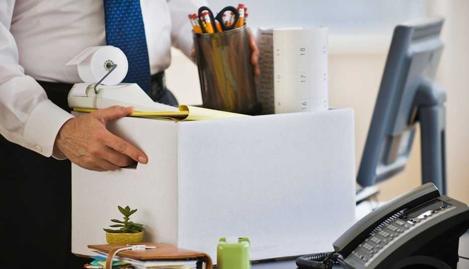 Manos de un hombre vestido con traje recogiendo sus objectos personales de un escritorio. Conoce tus derechos si eres despedido de tu trabajo.