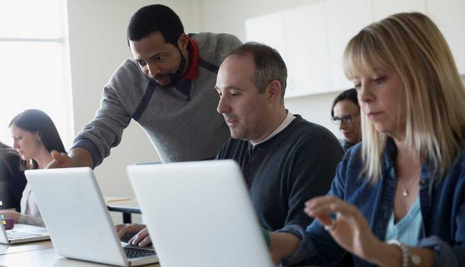 Adultos atienden a una clase de computadores.