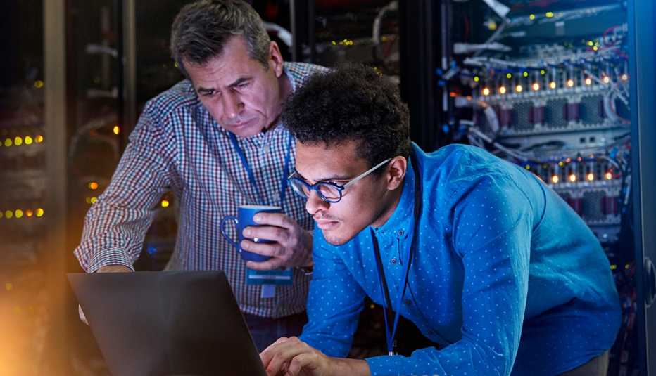 Dos técnicos viendo una computadora en un cuarto de servidores.
