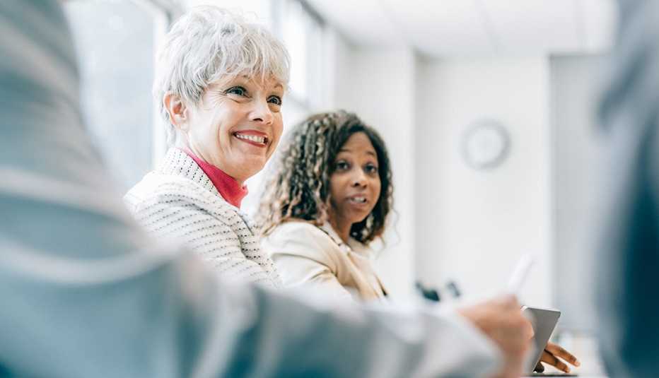 Mujer mayor sonriendo en una junta de trabajo
