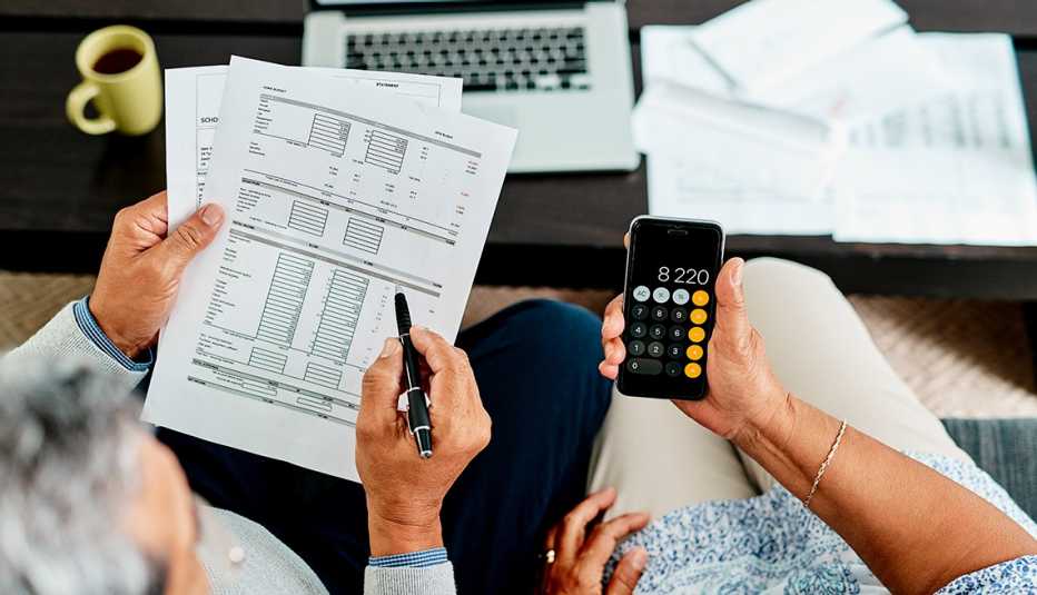 Pajera revisando cuentas de una factura, y usando la calculadora de un teléfono móvil.