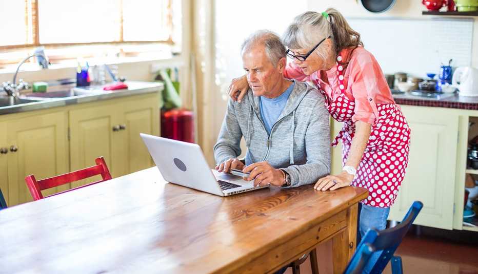 Pareja viendo una computadora en la cocina de su casa.
