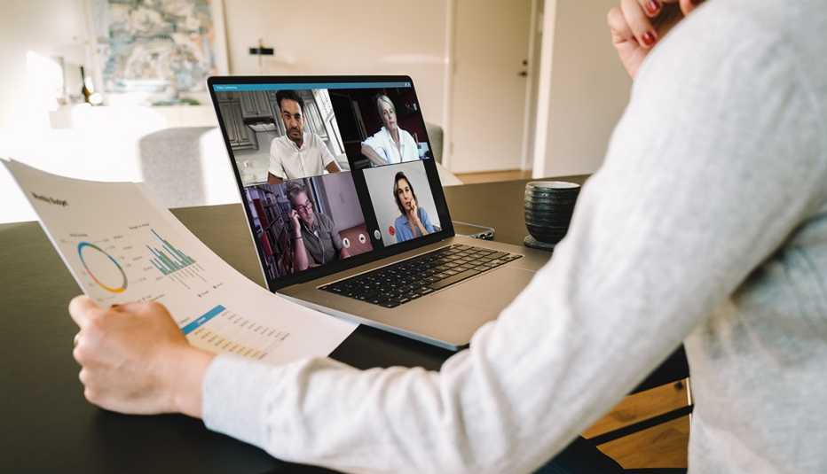 Una mujer sostiene documentos mientras está en una video conferencia desde la casa