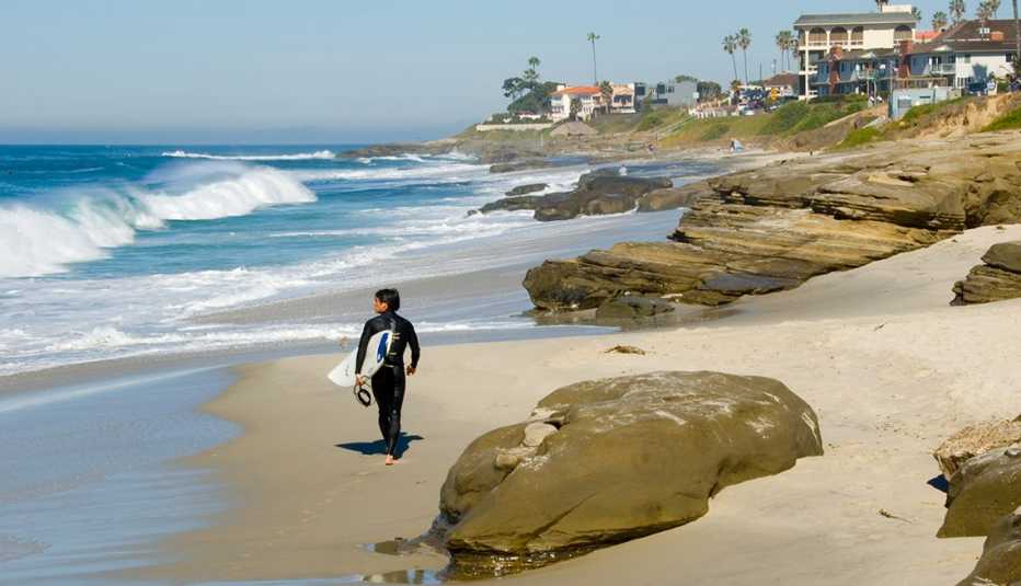 Surfista camina por la playa La Jolla en San Diego, California, EE.UU.