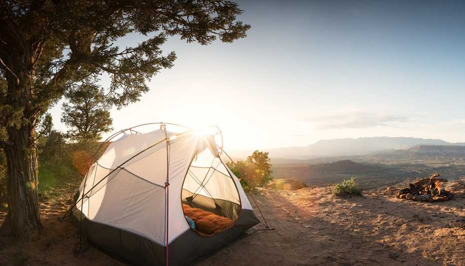 Tienda de campaña abierta durante el atardecer en una montaña