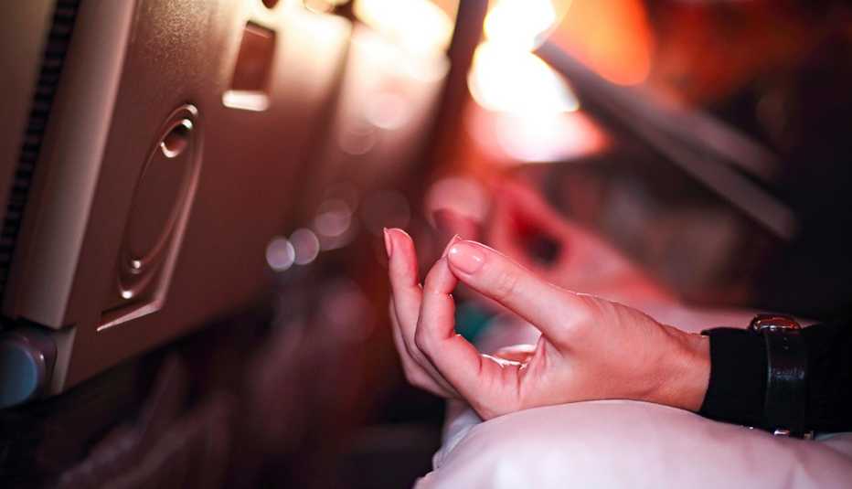 Persona en avión con aerofobia asustada de volar con miedo mientras está sentada en el asiento del avión y haciendo yoga para relajarse. Persona en avión con aerofobia asustada de volar con miedo mientras está sentada en el asiento del avión y haciendo yoga para relajarse.