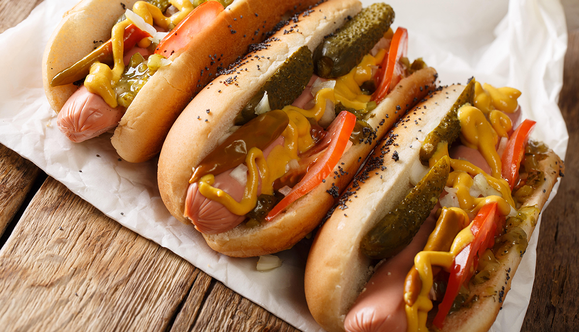 Perritos calientes hechos en casa al estilo de Chicago con mostaza, tomates, pepinos conservados en vinagre y cebollas.