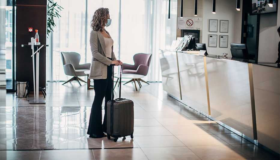 Mujer espera para registrarse en la recepción de un hotel