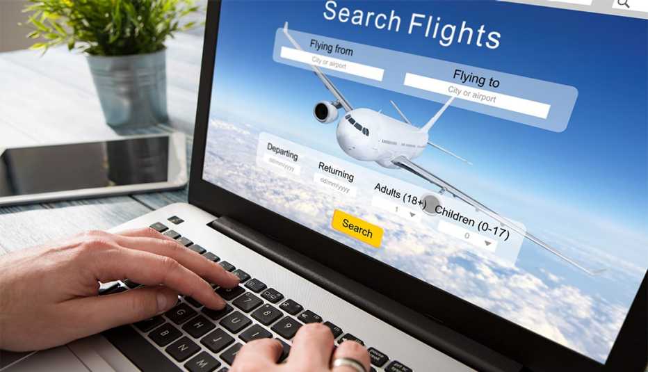 Persona usa una computadora portátil para reservar un vuelo en línea Persona usa una computadora portátil para reservar un vuelo en línea