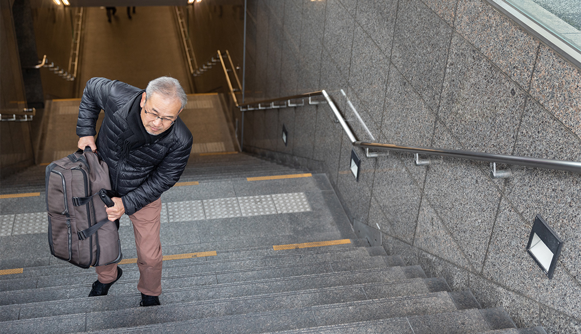 Hombre sube unas escaleras con su maleta de viaje