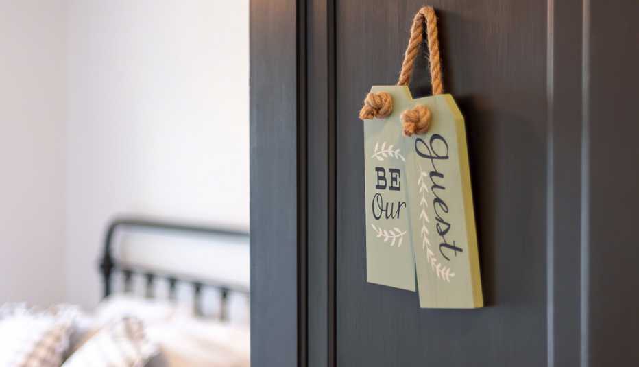 Cartel de madera en la puerta de un dormitorio que dice en inglés be our guest