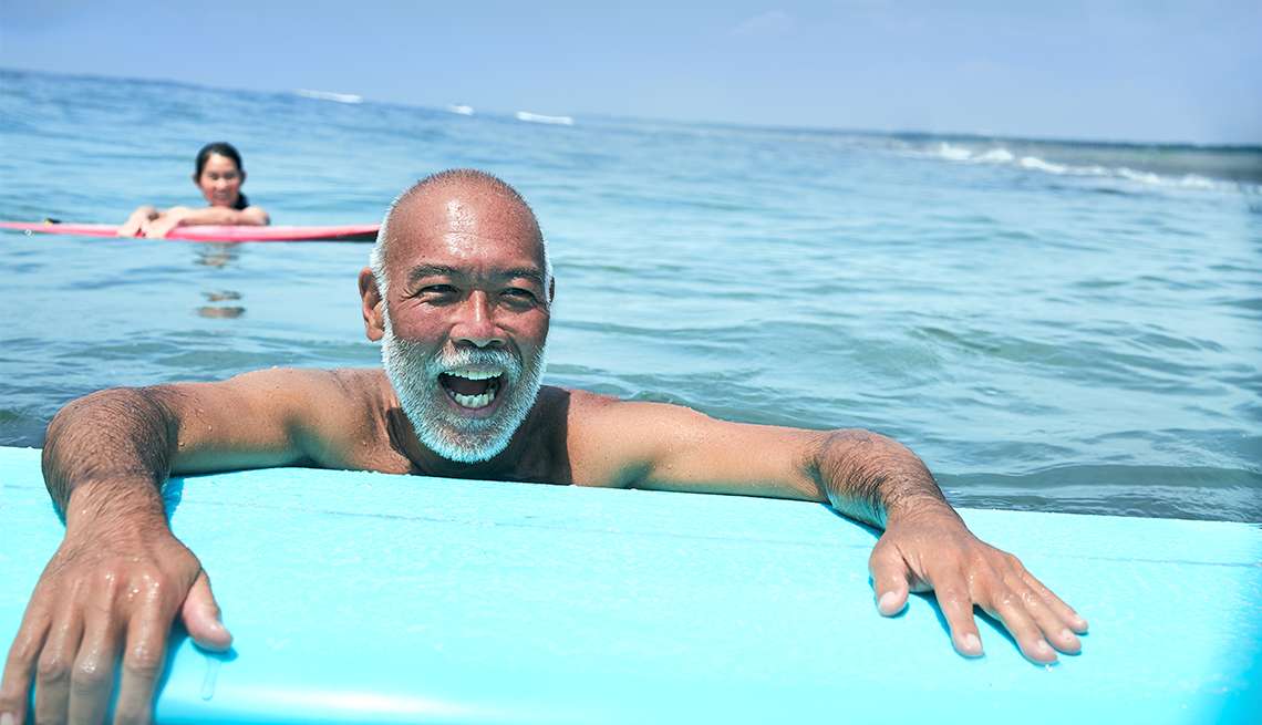 Un hombre y su esposa en el mar con tablas de surf