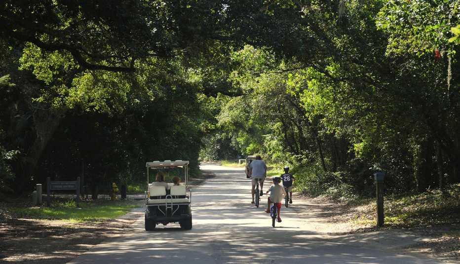 Personas en bicicleta y un carrito de golf en la isla Bald Head, Carolina del Norte