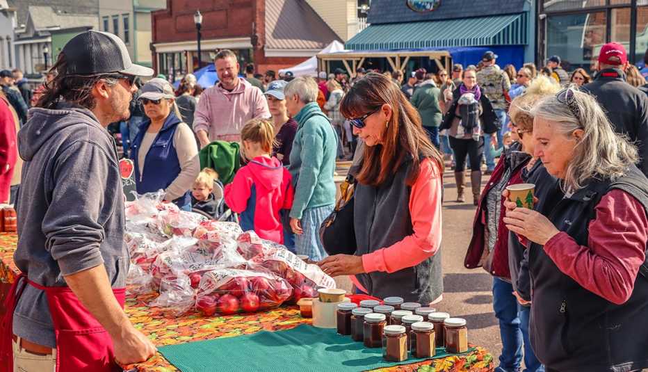 Visitantes del Bayfield Apple Festival examinan manzanas  y productos en jarras